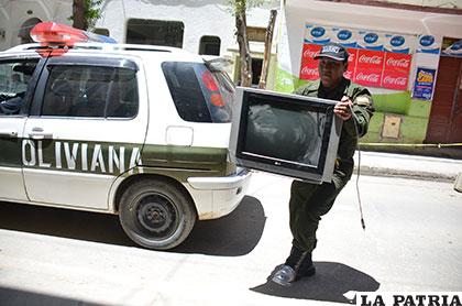 El televisor es cargado por un uniformado, como prueba del delito