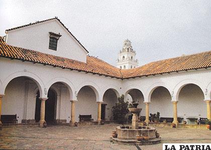 Claustro privado de la Compañía con la portada de ingreso a la Capilla Doméstica, al fondo la torre de la Iglesia de San Miguel, Sucre