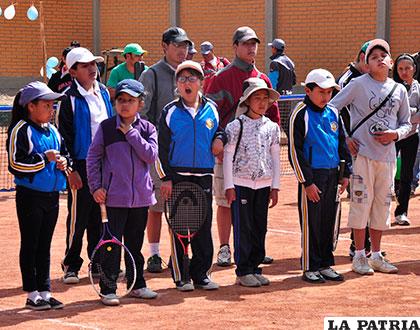 Niños y niñas que practican el tenis