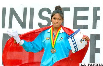 Dorca con la bandera de Oruro y la medalla de oro