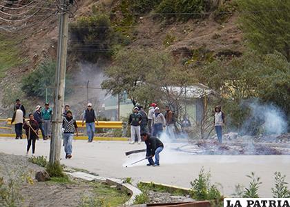 Un manifestante intenta devolver la granada de gas hacia los efectivos policiales