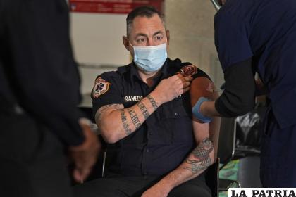 Un elemento de servicios médicos de emergencia de los bomberos de la ciudad de Nueva York y otros de sus compañeros son vacunados contra el COVID-19 /AP Foto /Seth Wenig, Archivo