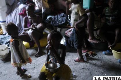 Una niña come mientras su madre amamanta a su hermano en un refugio para familias que han sido desplazadas por la violencia de pandillas en Puerto Príncipe, Haití /AP Foto /Matias Delacroix