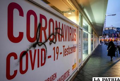 Una mujer camina junto a un centro de pruebas de COVID-19 abandonado en Fráncfort /AP Foto /Michael Probst