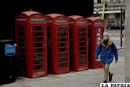 Un hombre camina junto a una tradicional cabina telefónica en Londres /AP Foto /Matt Dunham