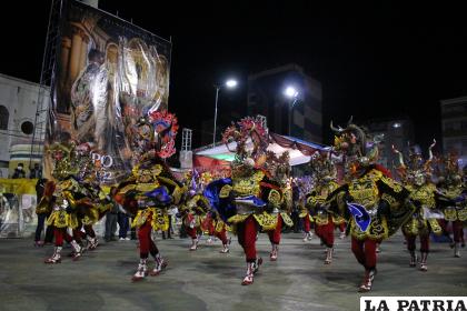 Tropa de diablos baila a los pies del afiche oficial del Carnaval de Oruro 2022 /LA PATRIA