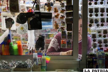 Una vendedora espera a sus clientes en un kiosco donde se venden mascarillas y guantes, entre otros artículos, en Moscú /AP Foto
