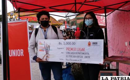 Saúl Rivera recibe el cheque de manos de la responsable de Investigación de la Unior, América Ayllón /LA PATRIA