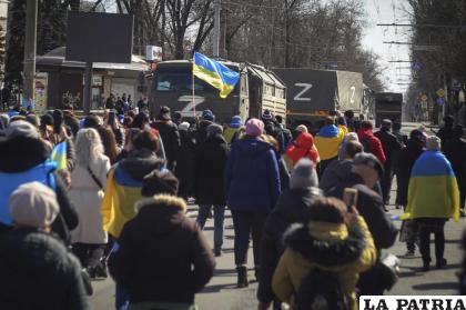 Personas con banderas ucranianas caminan hacia los camiones militares rusos durante una marcha contra la ocupación de Rusia /AP Foto, archivo