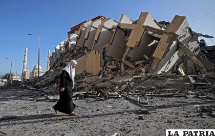 Una mujer camina en un lugar destruido tras los ataques /AFP