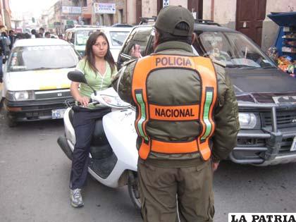 Un efectivo de Tránsito inspeccionando uso de casco en motociclistas