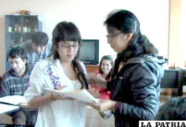 Una de las becarias recibe su certificado de manos de la docente María Elena Tovar