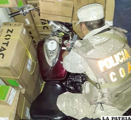 Un efectivo del COA junto a la motocicleta Harley Davidson, indicio que determinó la mercadería de contrabando
