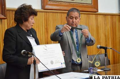 El rector de la UTO, Carlos Antezana y la gerente de Spectrolab, Rosario Mena, muestran el galardón