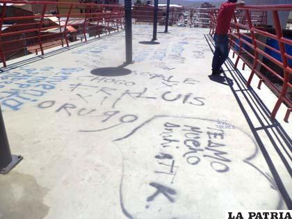 Grafitis en el piso de la pasarela de la 6 de Agosto y Montesinos