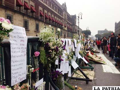 Manifestantes dejan flores frente a Palacio por Ayotzinapa
