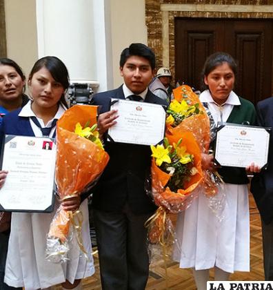 Carlos Tordoya (centro) junto a las otras dos estudiantes que recibieron el incentivo a la excelencia escolar