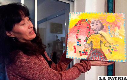 La artista Sulma Montero sostiene un cuadro pintado por una niña