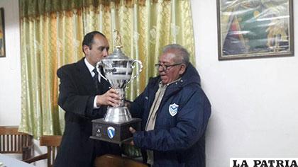 Osvaldo Concha, entrega el trofeo de campeón a Víctor Gonzales, directivo de EM Huanuni
