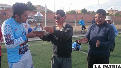 Víctor Mamani recibe el trofeo de campeón de manos de René Huallata