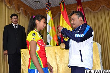 Marcelo Taborga entrega la medalla de distinción a Nicole Rafael