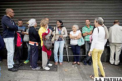 Personas realizan una fila para entrar a un automercado que acepta pagos en Petro
