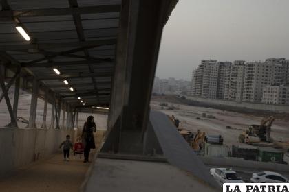 Una mujer y su hijo caminan por una rampa peatonal junto al lugar donde Israel planeaba construir un enorme asentamiento judío /AP Foto /Maya Alleruzzo, archivo