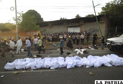 Varios cuerpos dentro de bolsas permanecen a la orilla de una carretera después de un accidente /AP Foto
