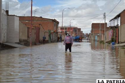 Una señora camina en medio de la calle anegada /LA PATRIA