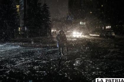 Una mujer cruza una calle durante una nevada, en pleno apagón en Kiev /AP Foto/Felipe Dana