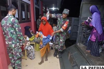 Soldados indonesios ayudan a mujeres y niños rohinyás a salir de un vehículo militar al llegar a un albergue temporal /AP