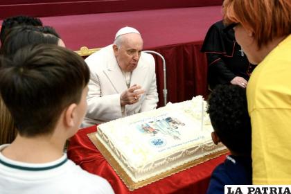 El papa Francisco sopla una vela de su pastel de cumpleaños rodeado de niños /EFE